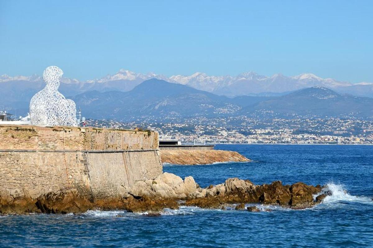 ένα άγαλμα ενός άνδρα που κάθεται σε έναν τοίχο με θέα το νερό