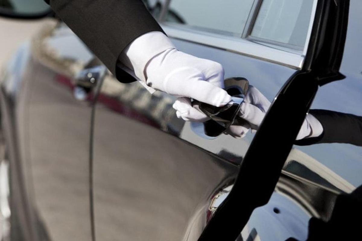 a person in a suit and gloves is opening a car door