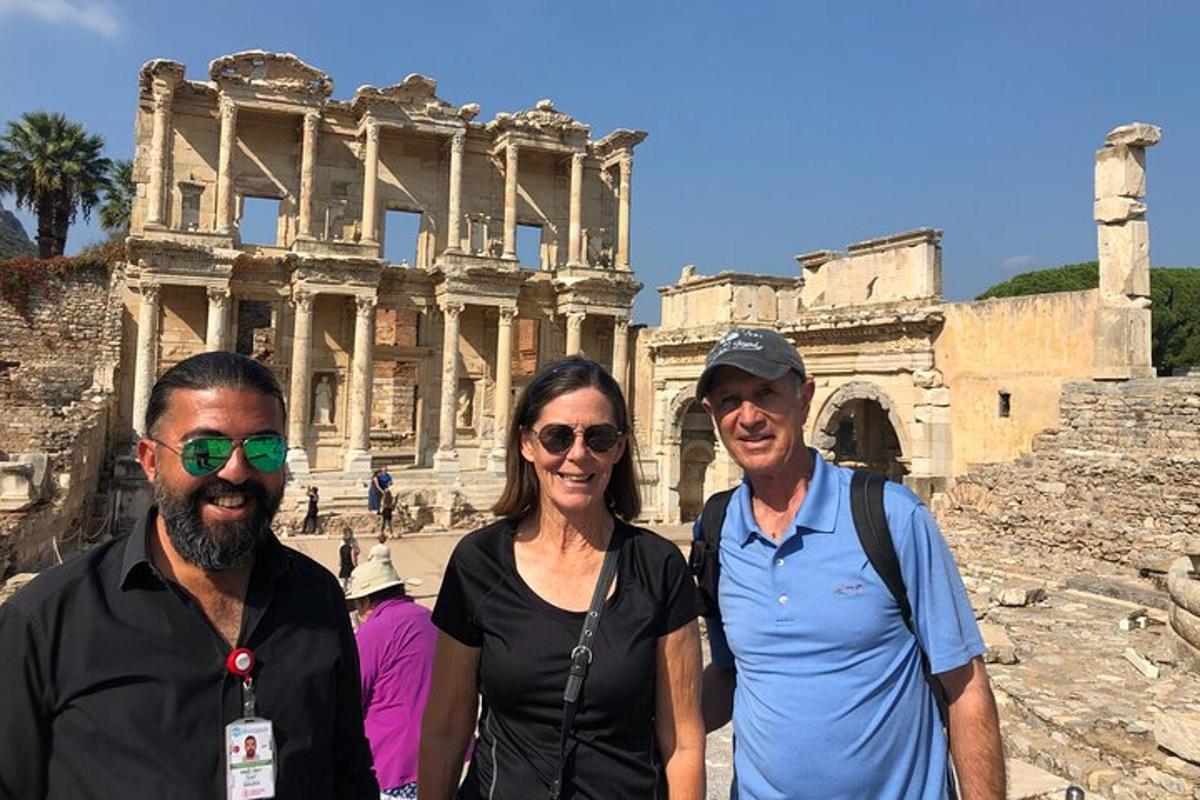 two men and a woman standing in front of the coliseum