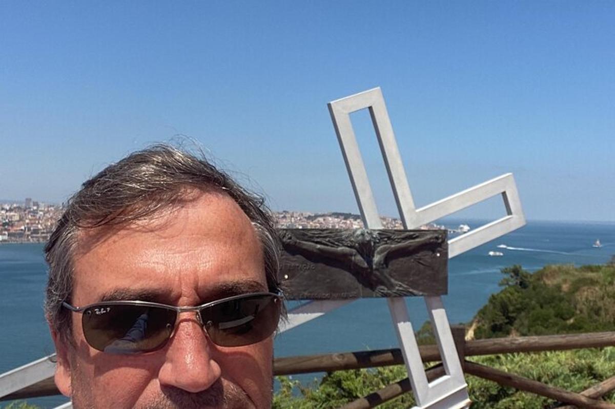 egy napszemüveges férfi áll egy kereszt mellett