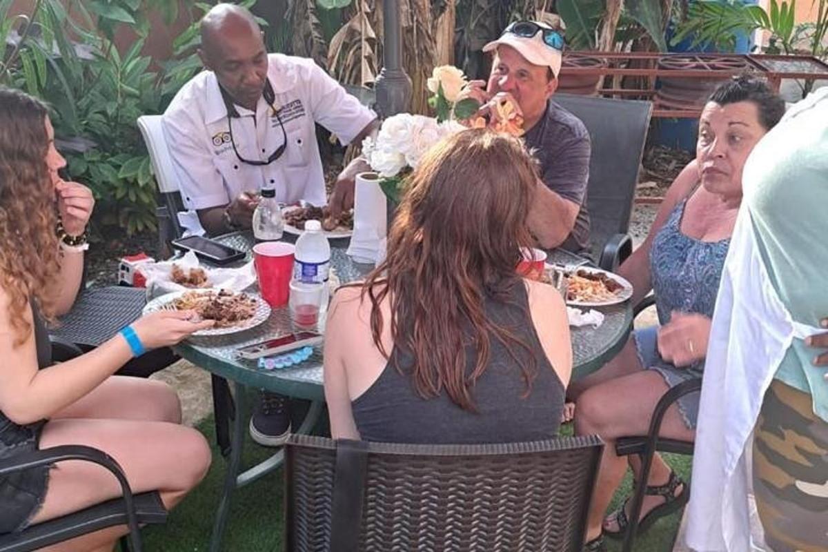 isang grupo ng mga tao na nakaupo sa paligid ng isang mesa na kumakain ng pagkain