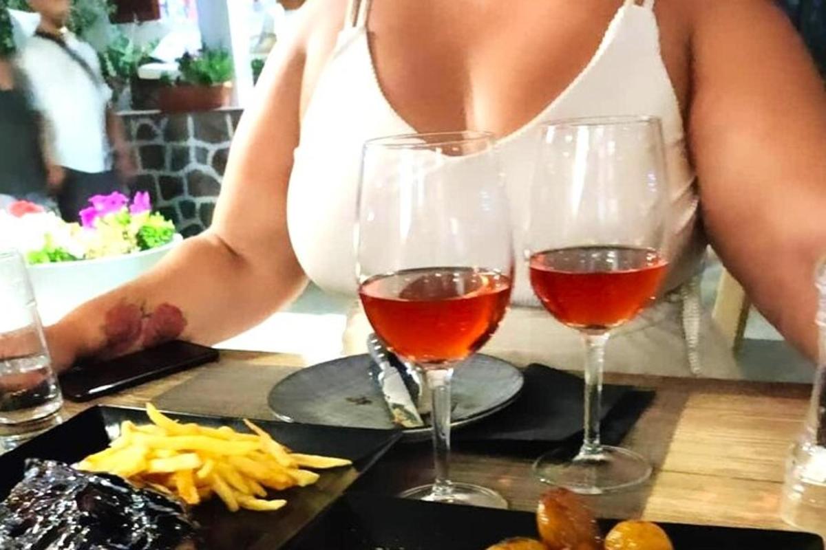 žena sedící u stolu se dvěma sklenicemi vína
