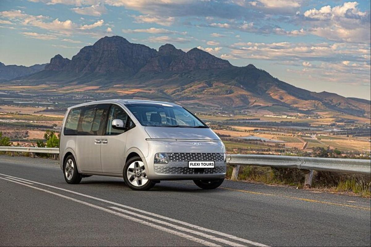 a small van driving down a road with mountains in the background