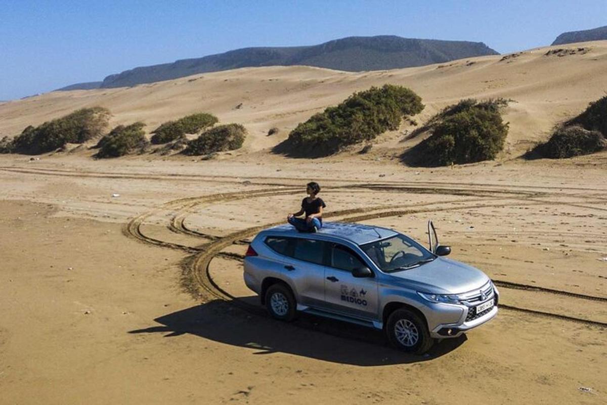 a person sitting on top of a suv in the desert