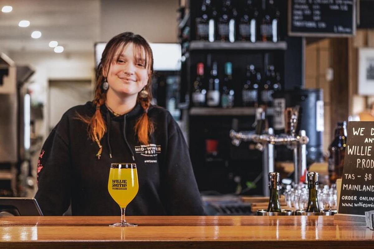 kona situr við bar með glas af víni