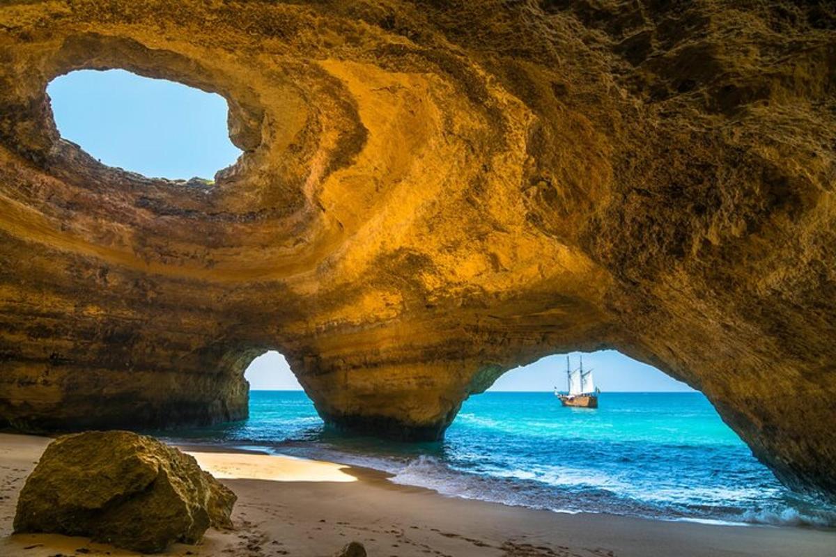uma praia com uma caverna rochosa e um barco na água