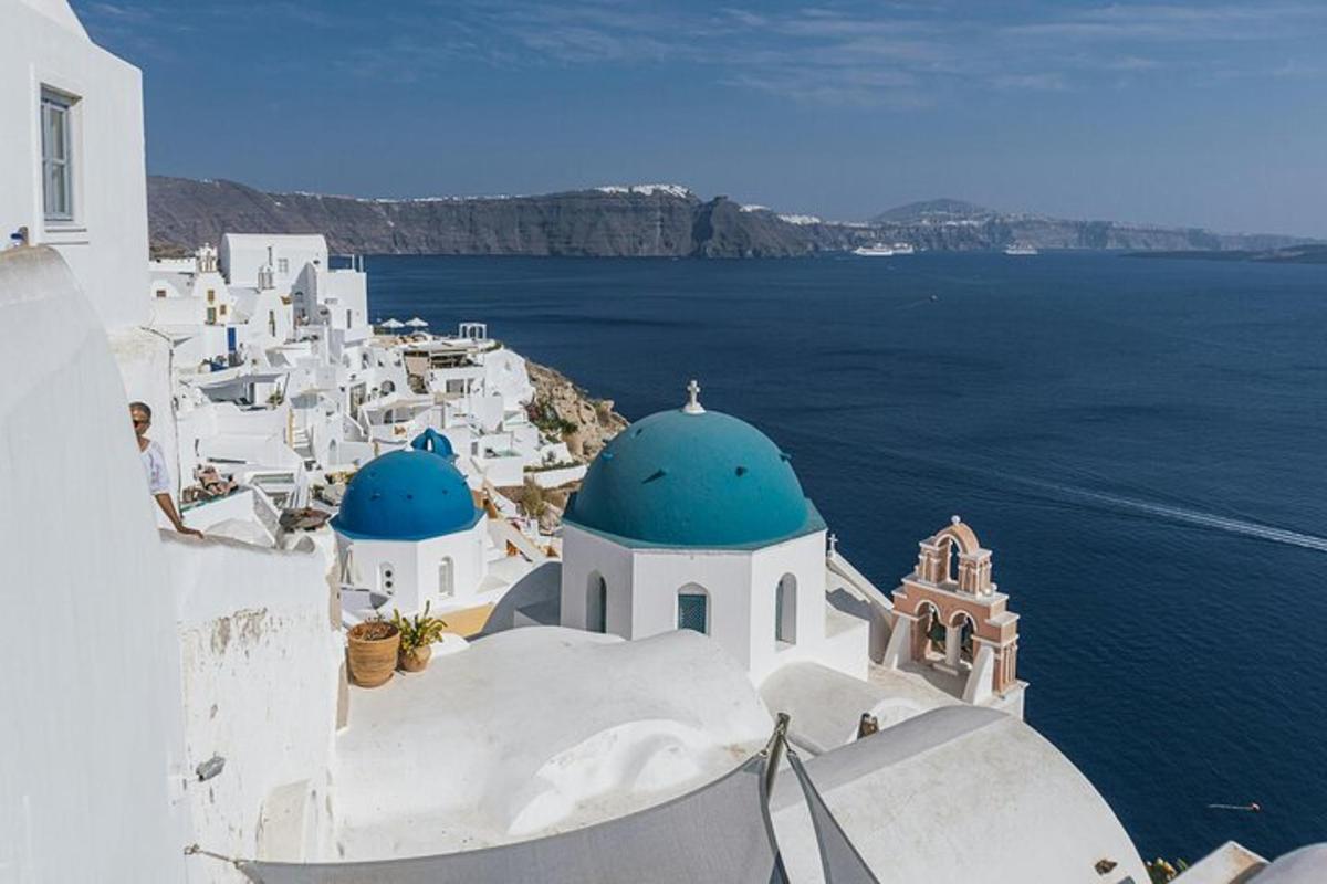 μια ομάδα λευκών κτιρίων με μπλε θόλους και τον ωκεανό