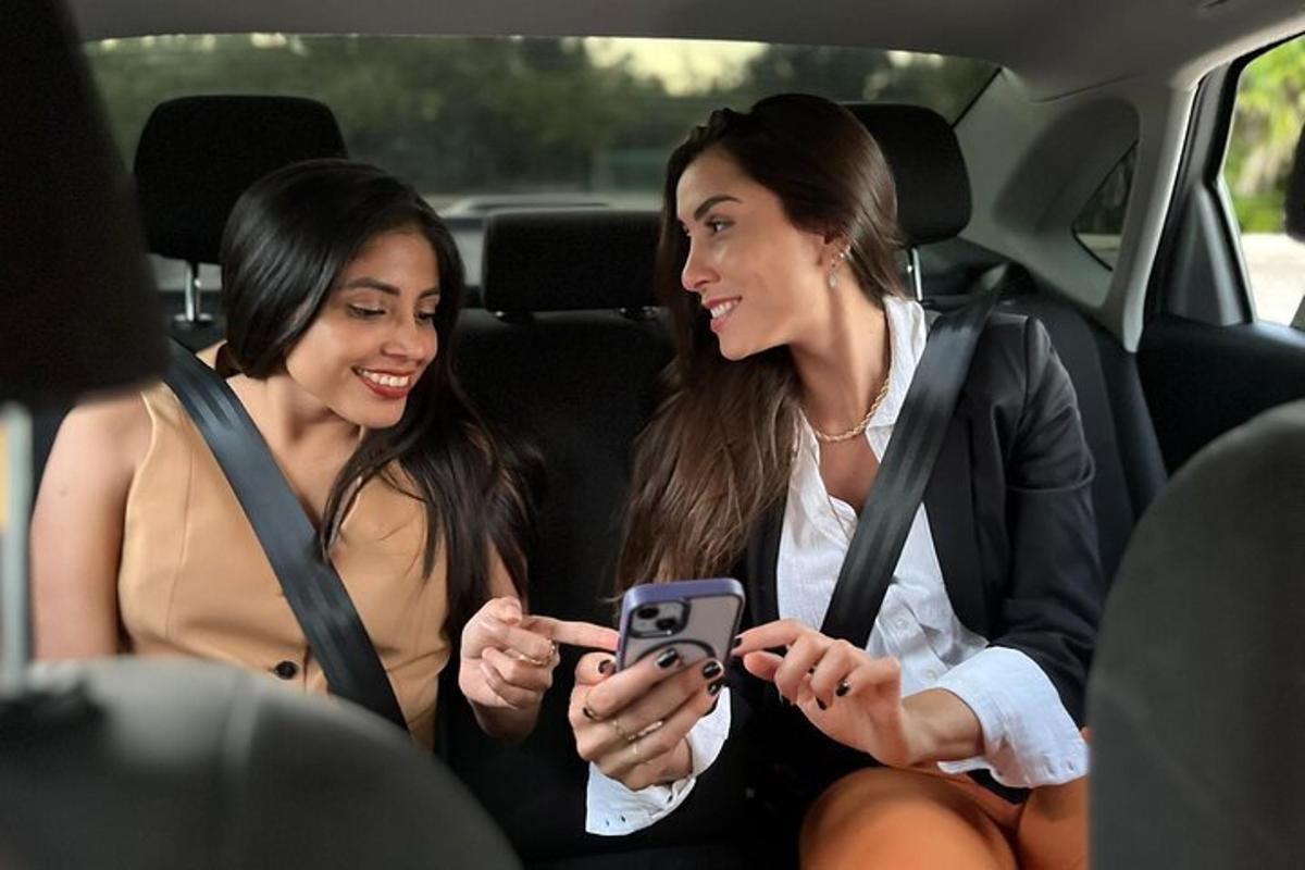 Két nő ül egy autó hátuljában, és a mobiltelefonjukat nézegetik