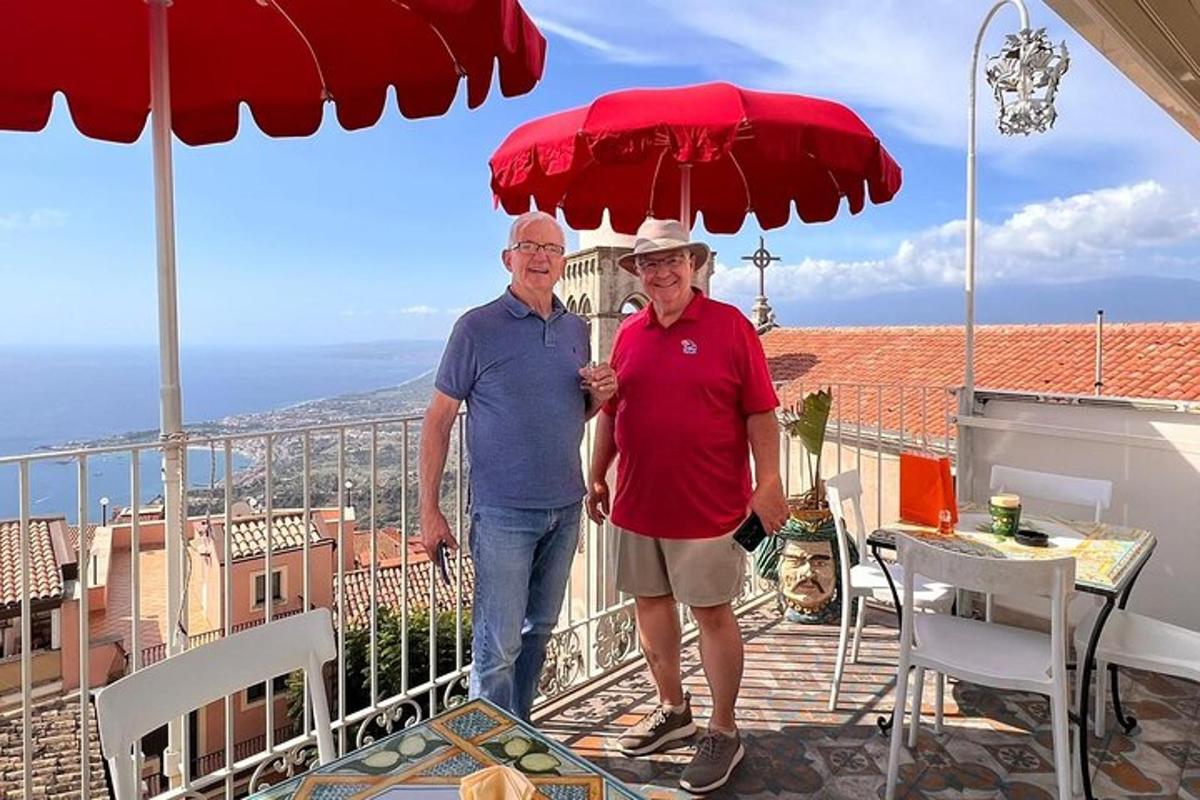 dvaja starší muži stojaci na balkóne pod slnečníkom