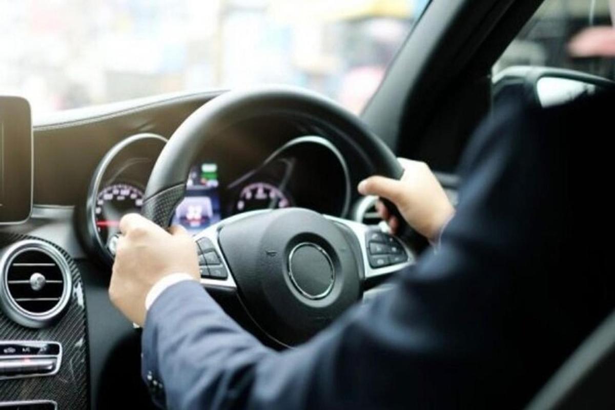 muž řídící auto s rukama na volantu