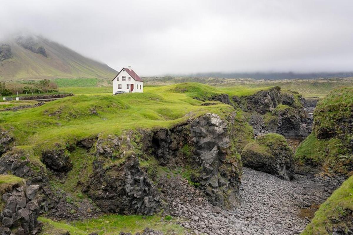 una petita casa blanca en un turó cobert de molsa
