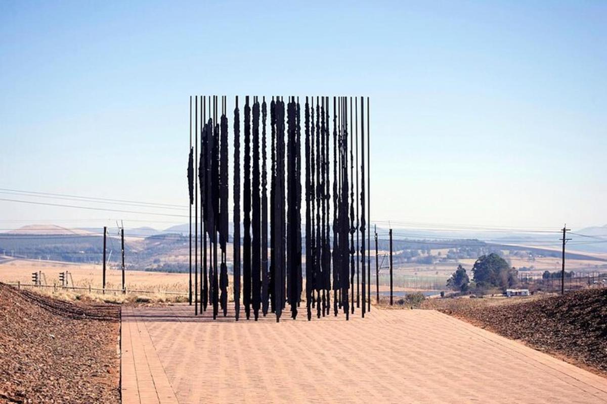 una escultura de pals negres en un camí de terra
