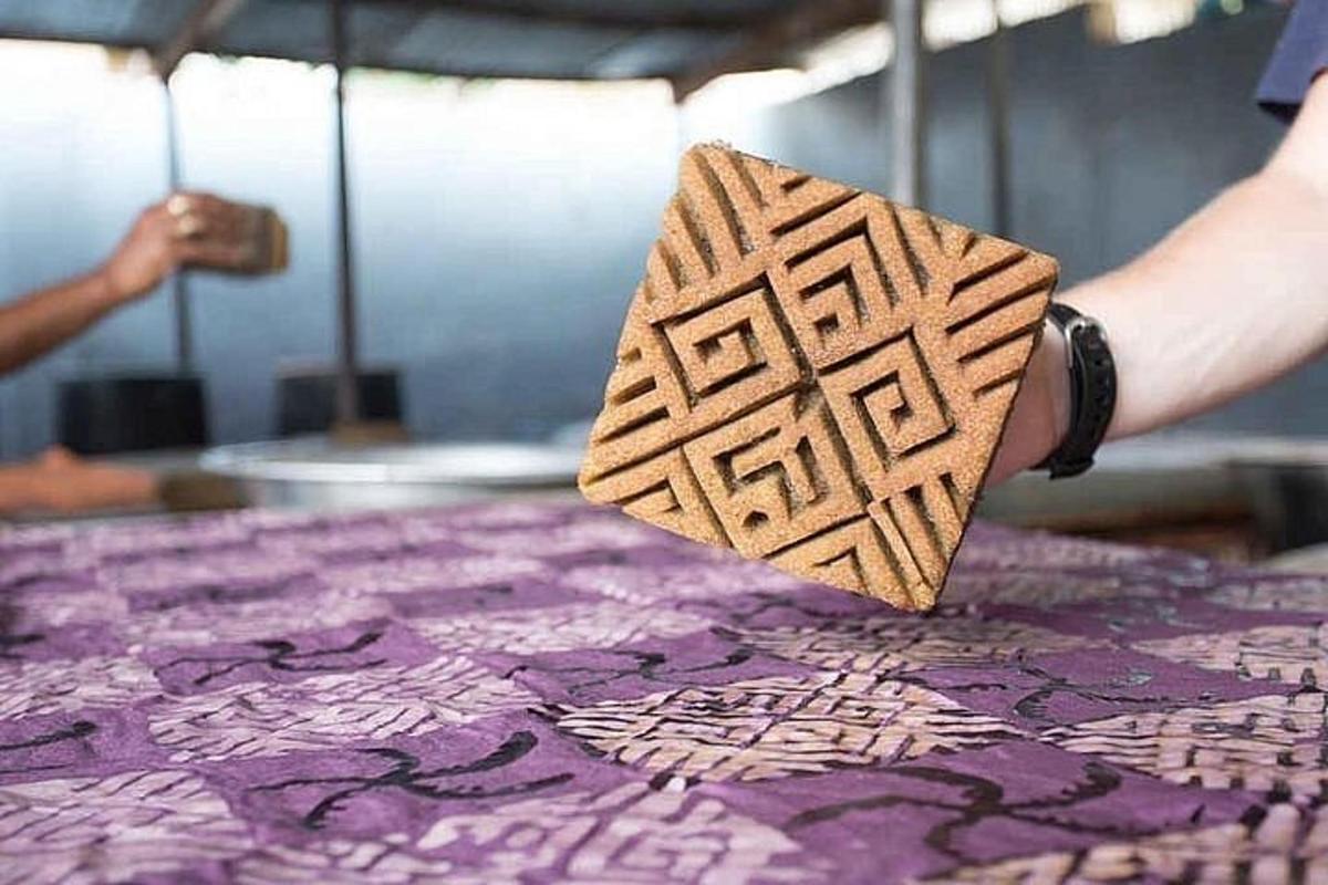una persona tiene in mano un'opera d'arte su un tappeto viola