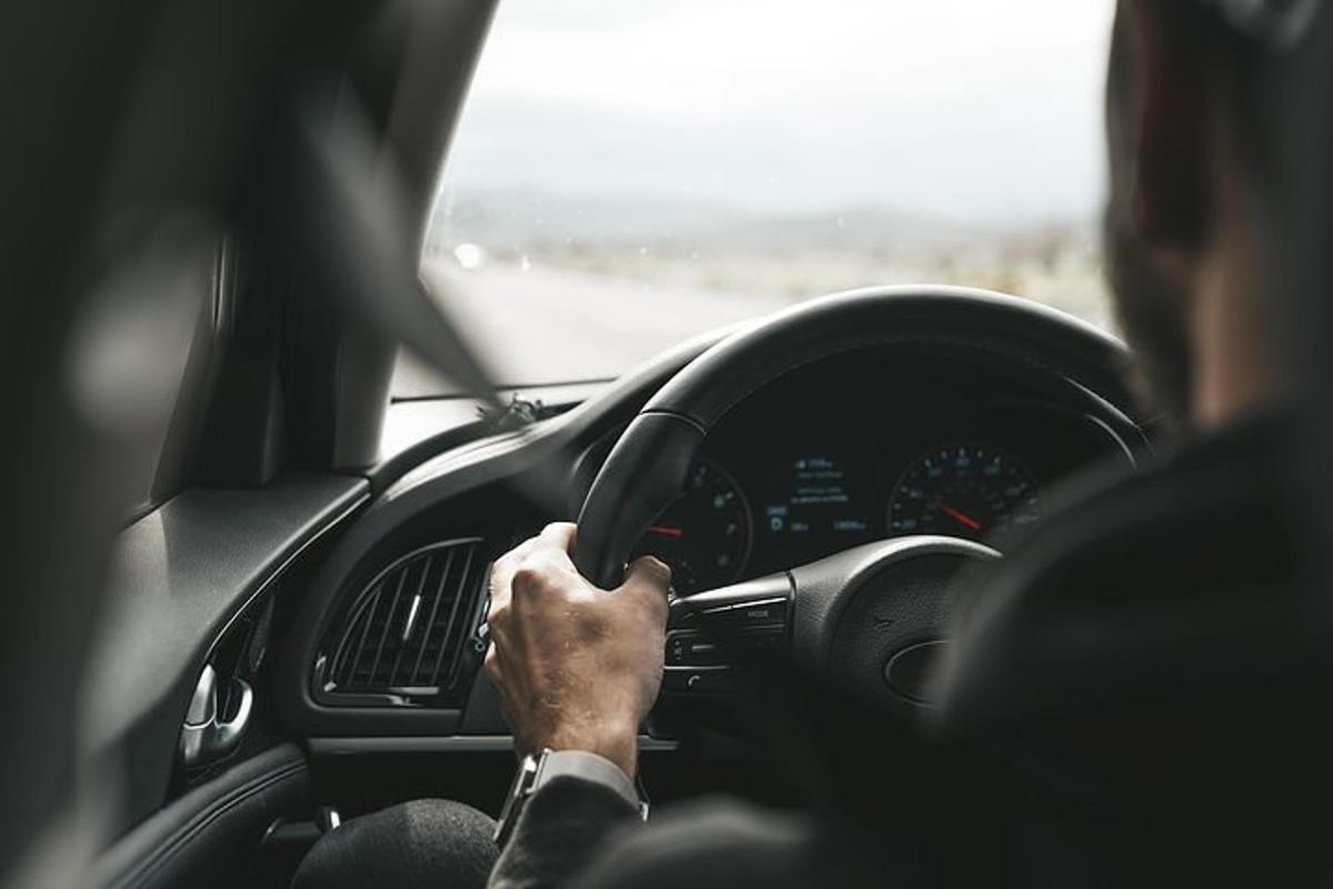 a woman driving a car with her hand on the steering wheel