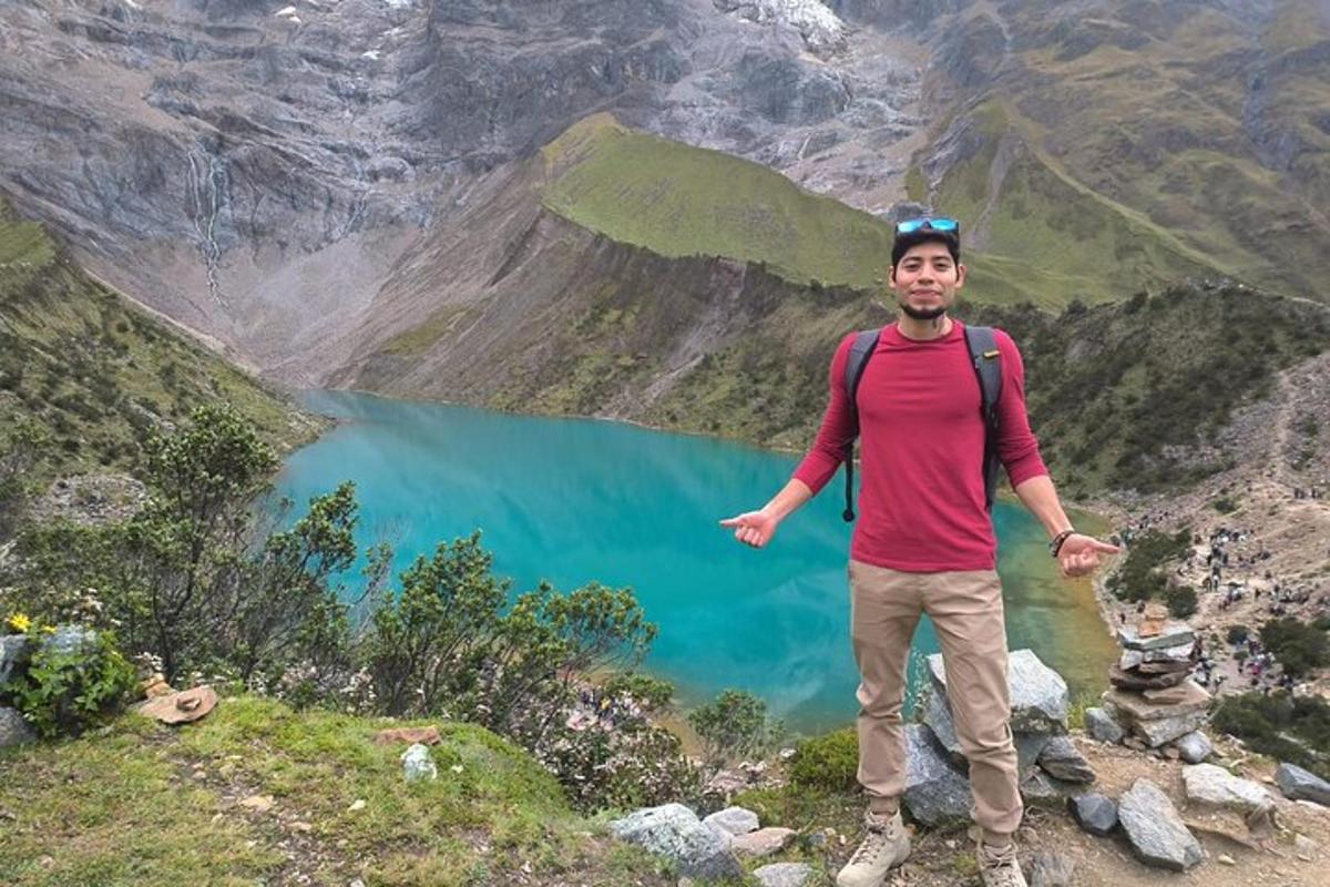 seorang pria berdiri di atas gunung dengan danau