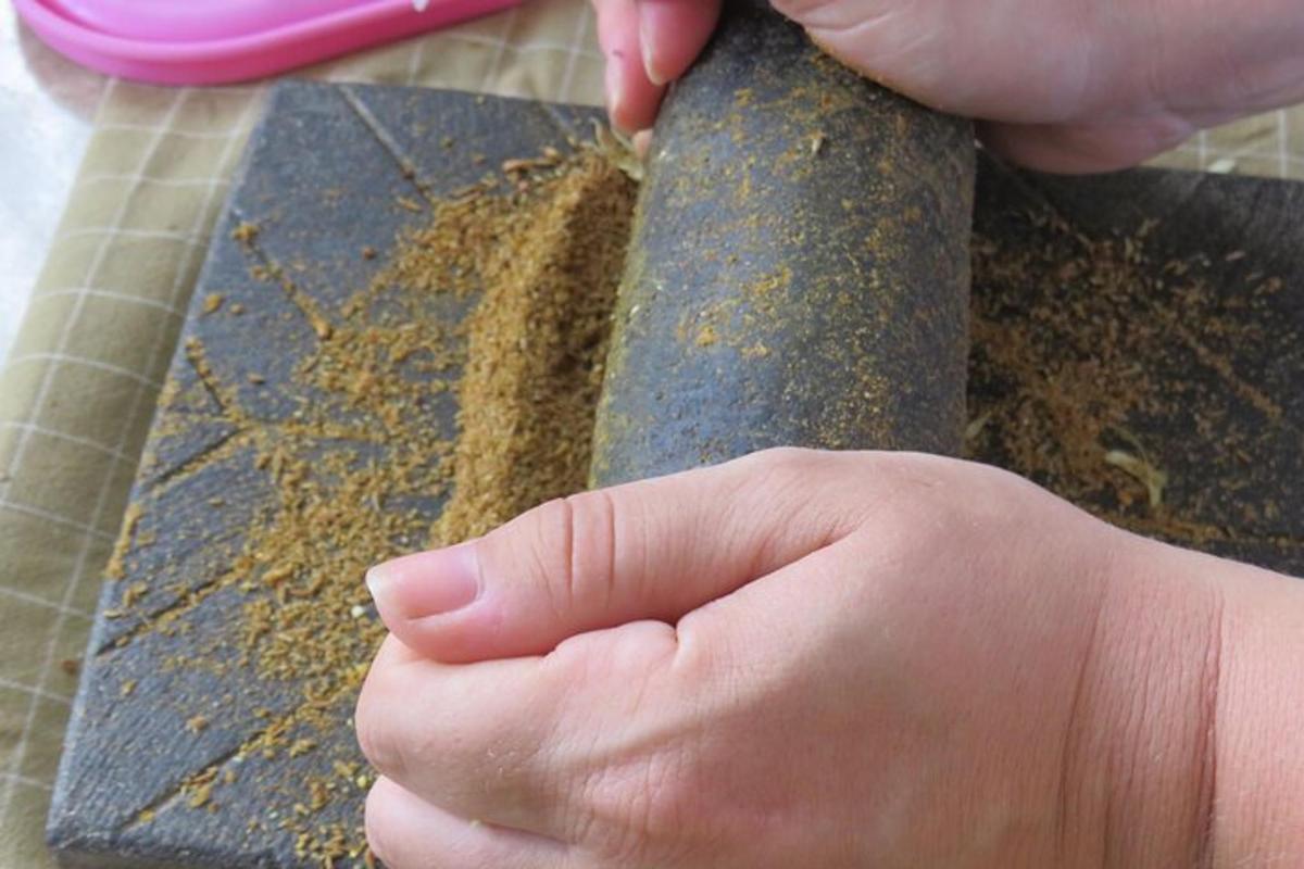 una persona sosteniendo un cuchillo con tierra en una tabla de cortar