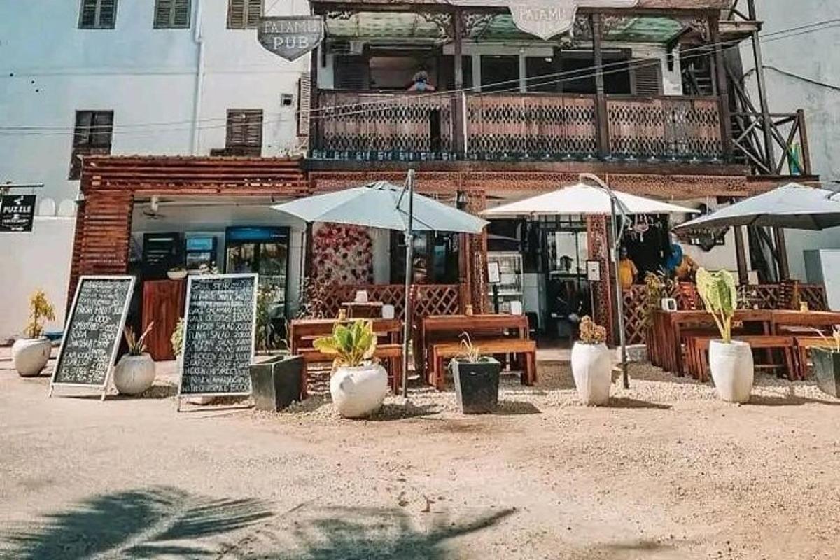 restaurace se stoly a slunečníky před budovou