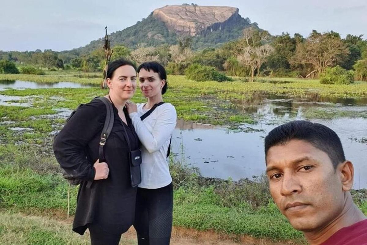 two women and a man standing next to a body of water