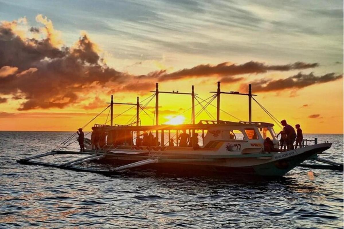 a group of people on a boat in the water at sunset