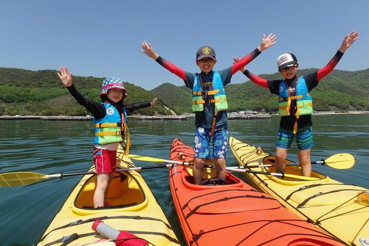 three children are standing on kayaks on the water
