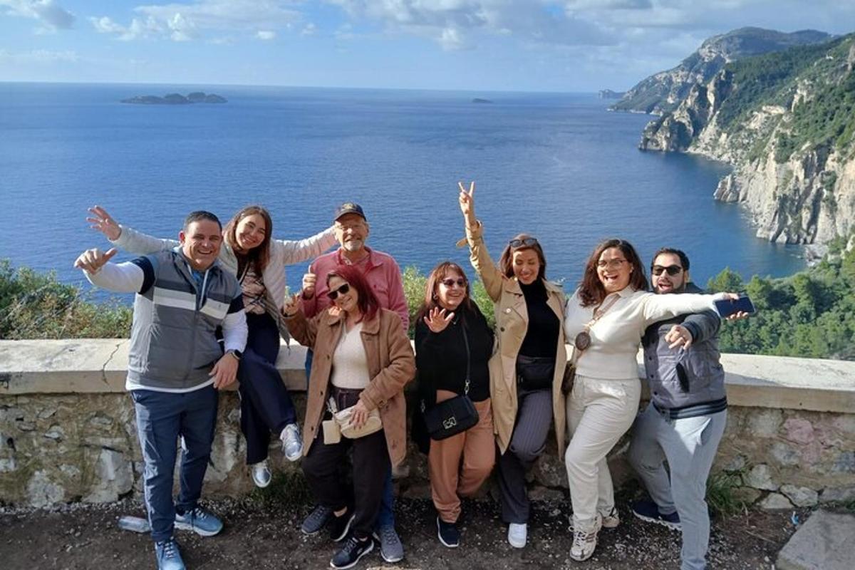 skupina ljudi, ki stojijo na zidu blizu oceana