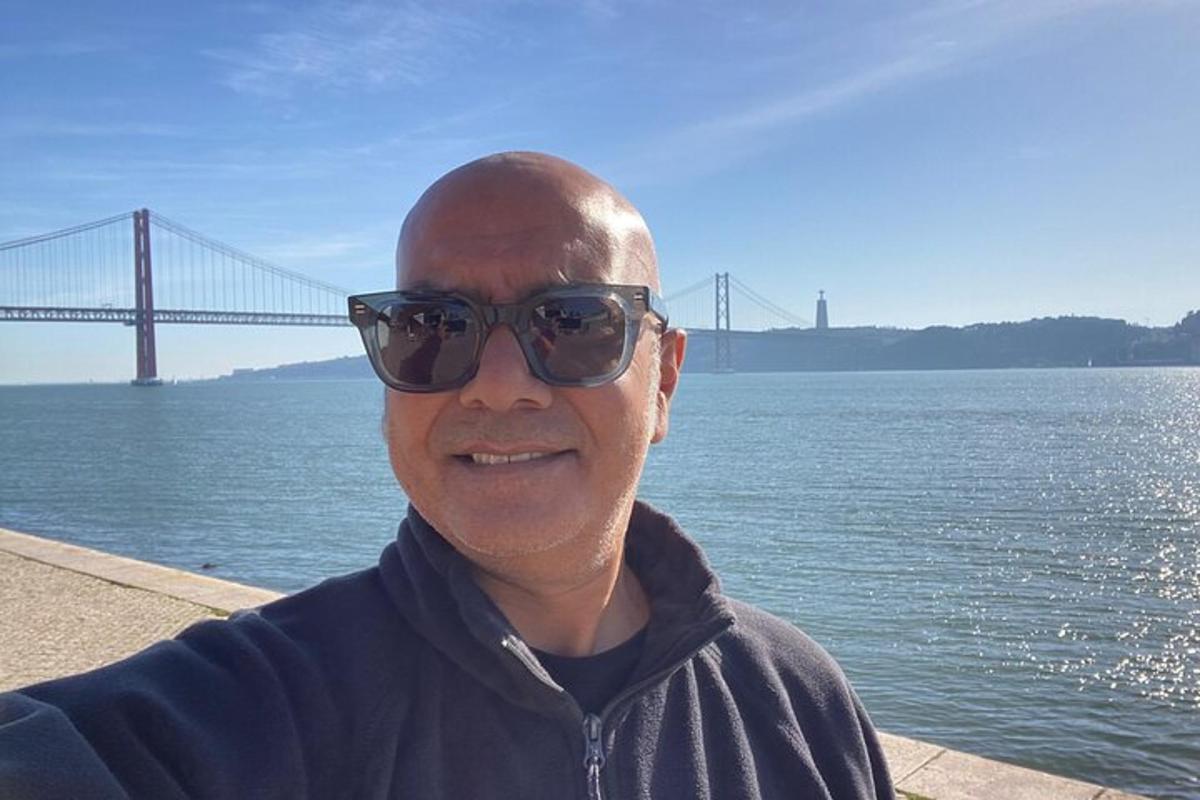un uomo con occhiali da sole in piedi davanti a un ponte