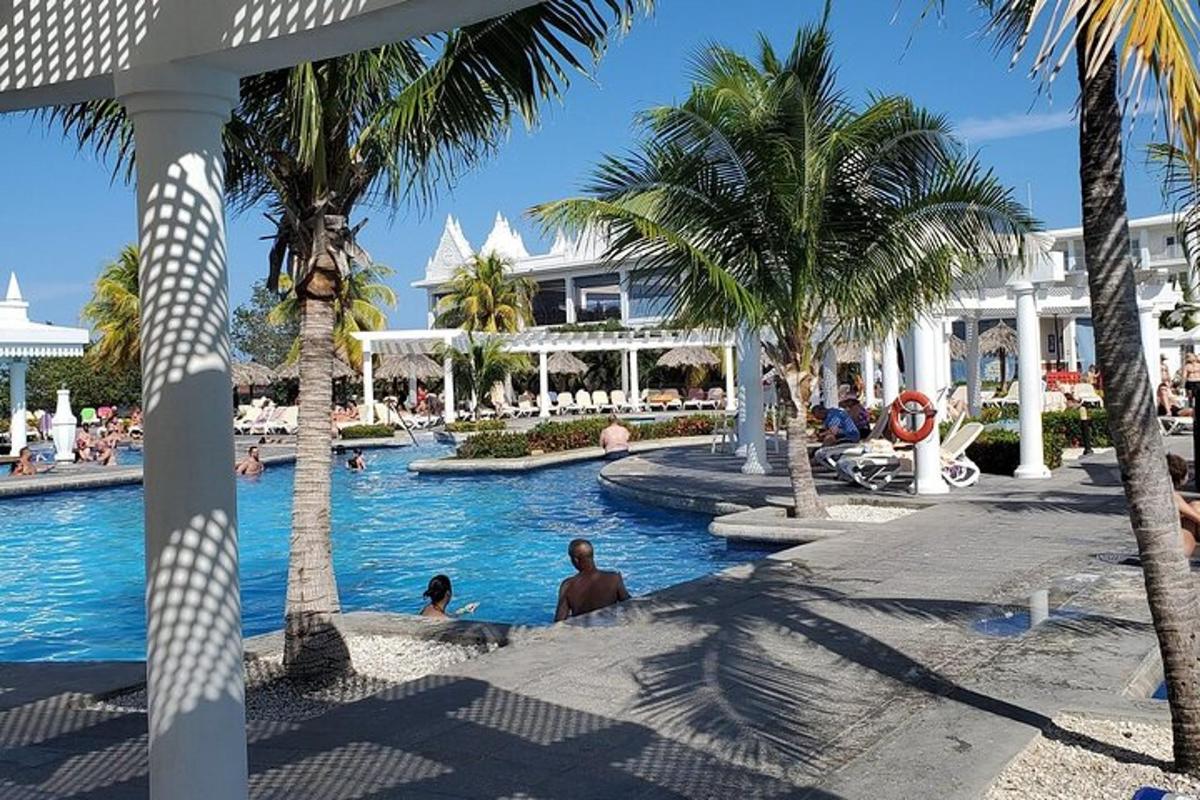 ein Pool in einem Resort mit Palmen und Menschen darin