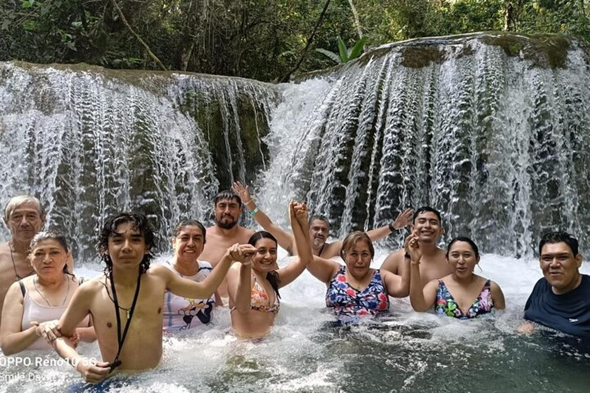 a group of people posing in front of a waterfall