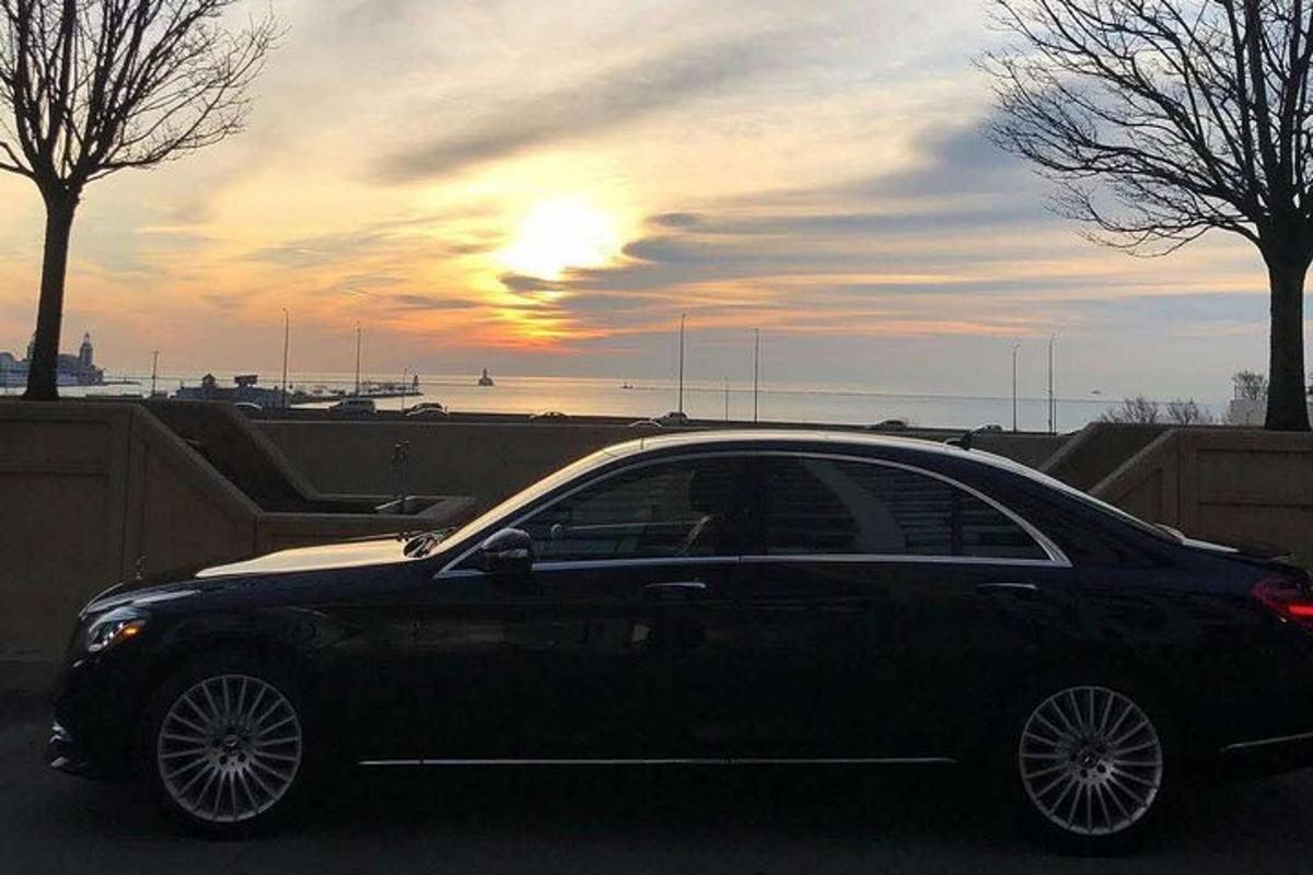 a black car parked in a parking lot with the sunset