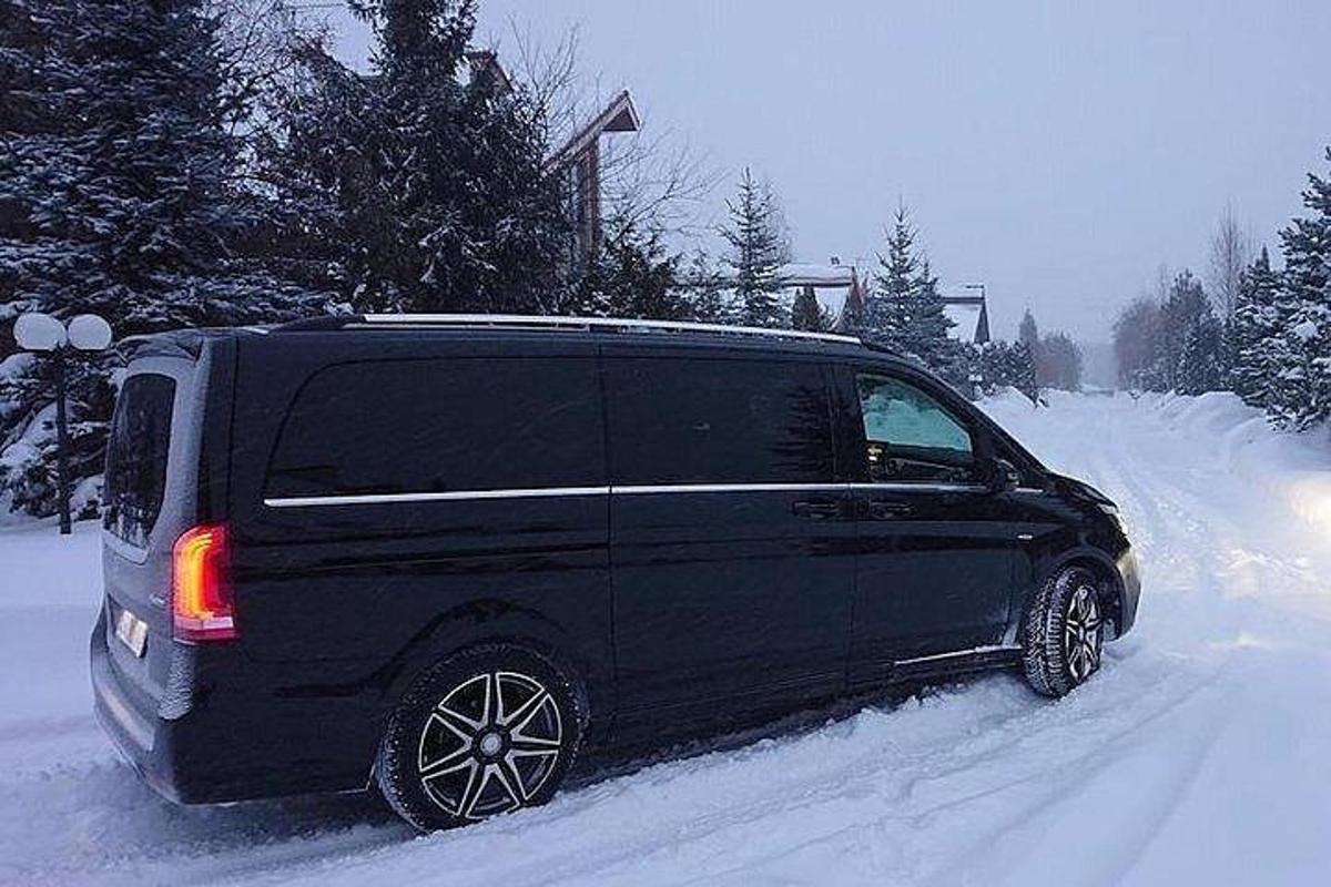 una furgoneta negra aparcada en una carretera coberta de neu