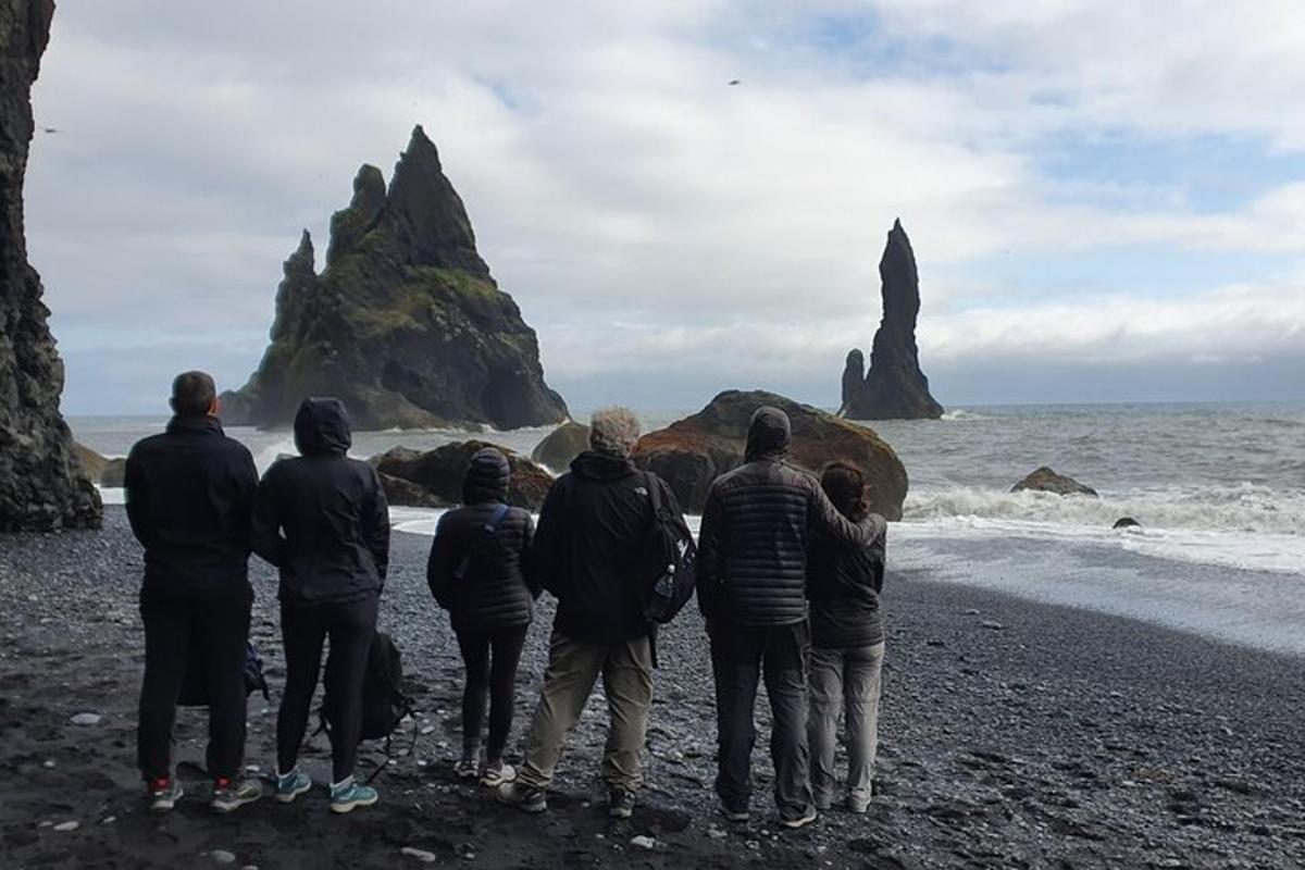 un gruppo di persone in piedi sulla spiaggia che guardano l'oceano