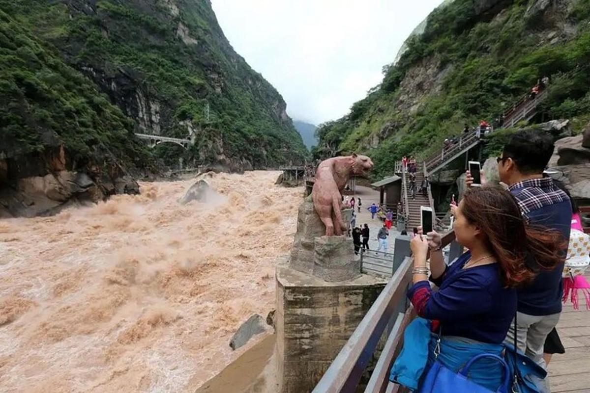 a woman taking a picture of a statue in a river