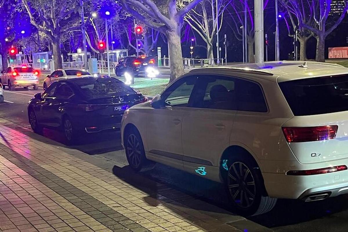 dois carros estacionados na beira de uma rua à noite