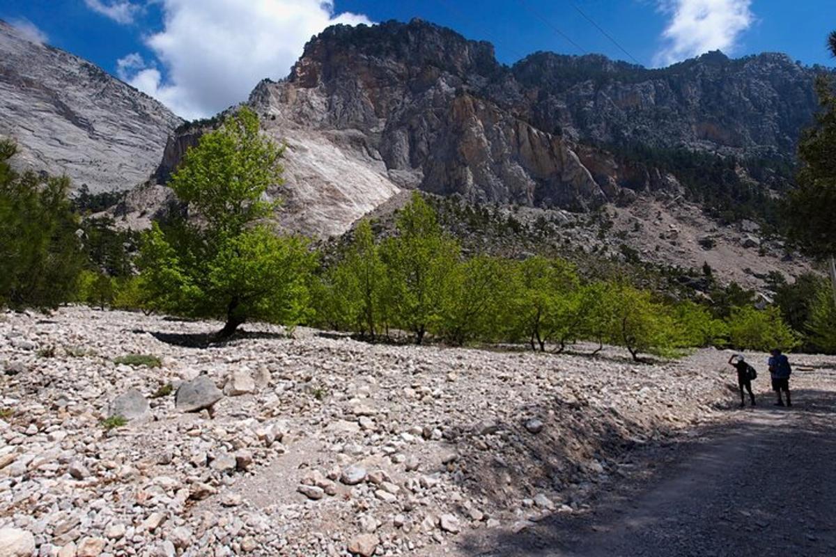 dua orang berjalan di jalan berbatu di gunung
