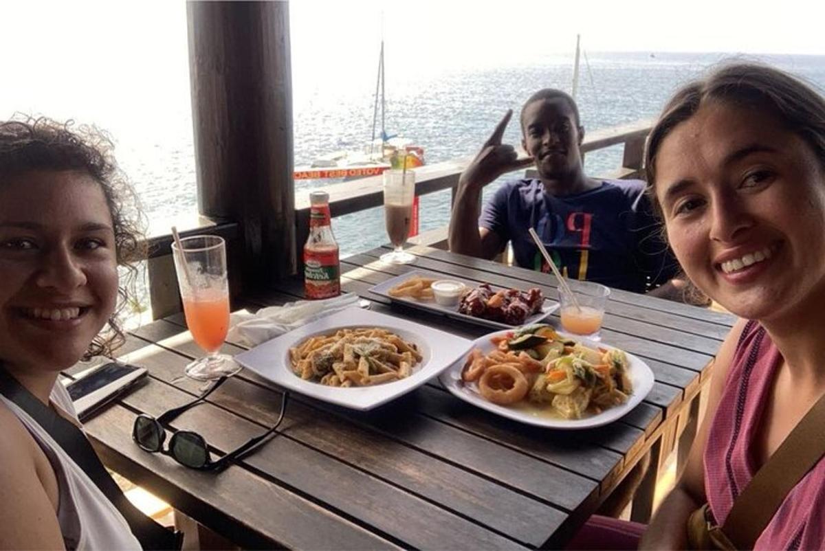 Dos mujeres y un hombre sentados en una mesa con platos de comida.
