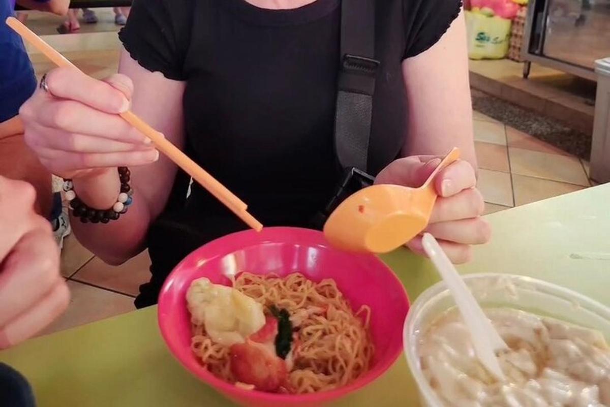 una persona sosteniendo un tazón de fideos con palillos