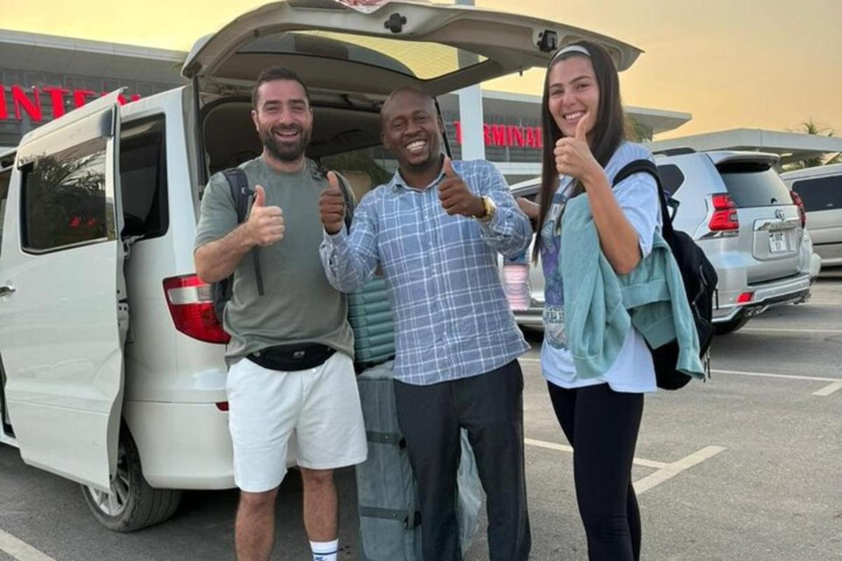 two men and a woman giving thumbs up in front of a van