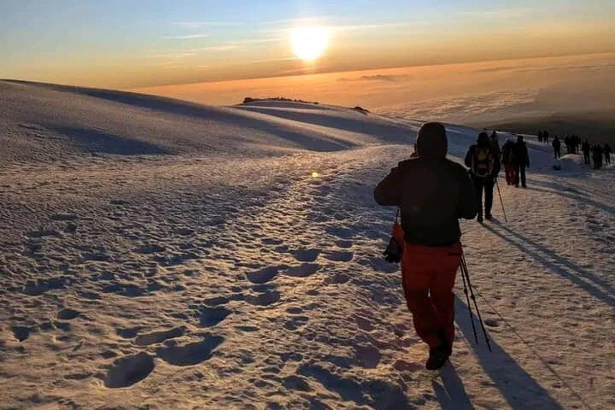 sekumpulan orang berjalan mendaki gunung yang dilitupi salji