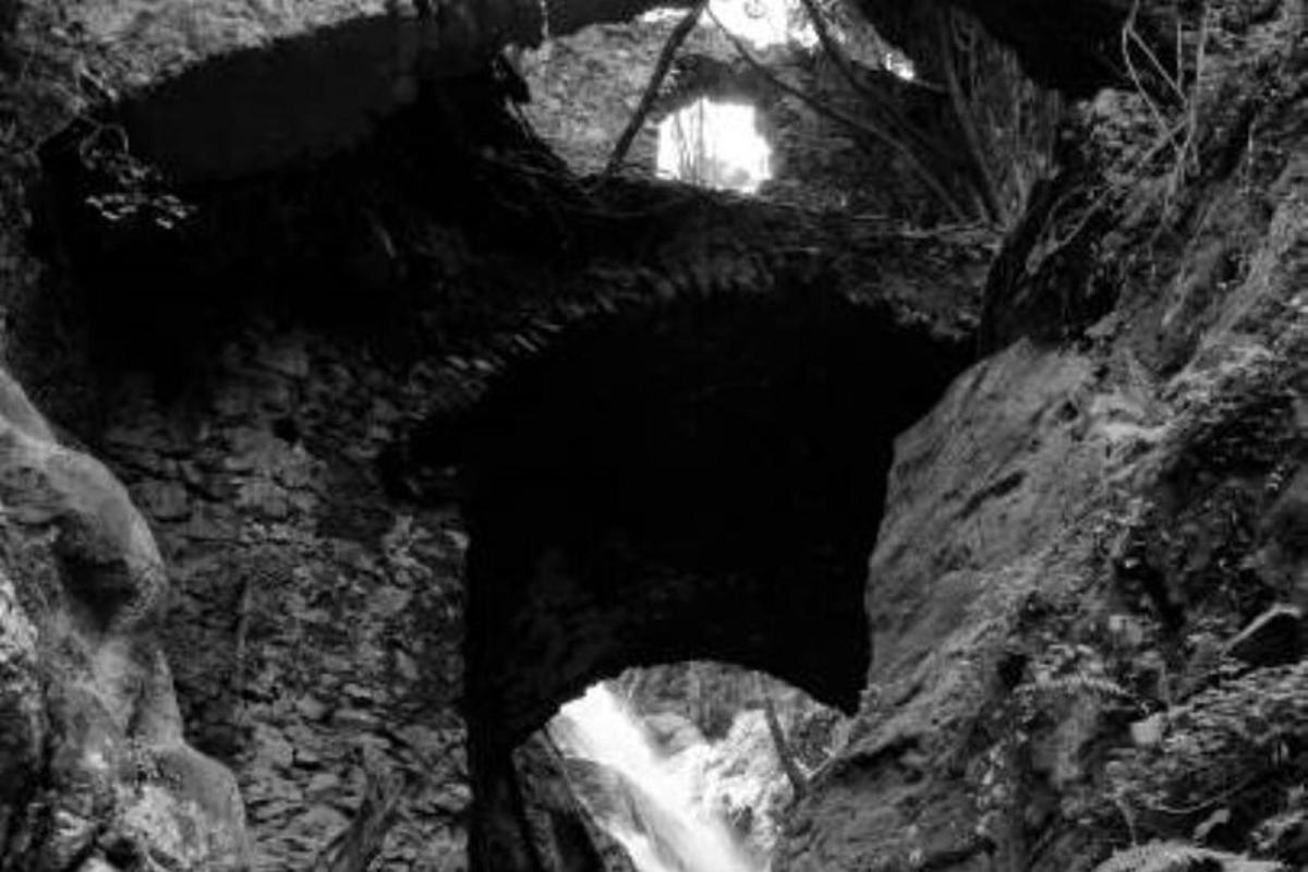 černobílá fotografie tunelu s vodopádem