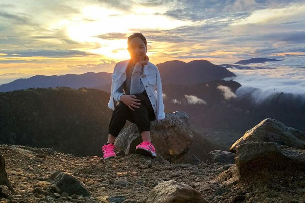 a woman sitting on a rock on top of a mountain