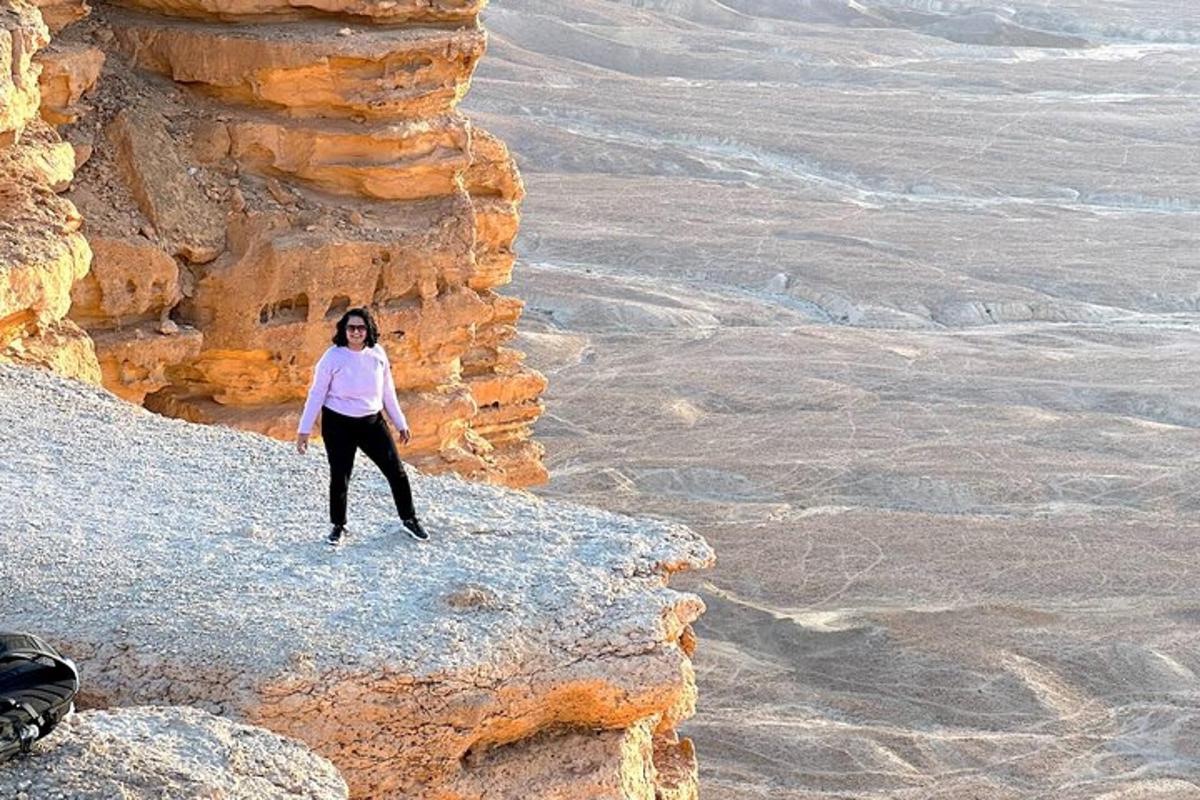 una donna in piedi su una scogliera nel deserto