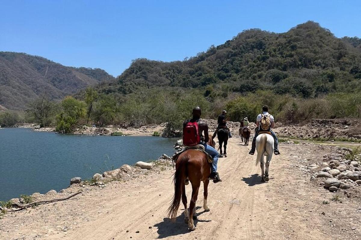 a group of people riding horses down a dirt road