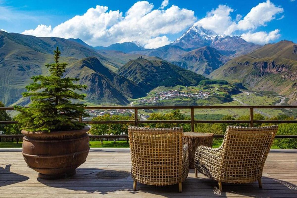 twee stoelen en een potboom op een terras met bergen