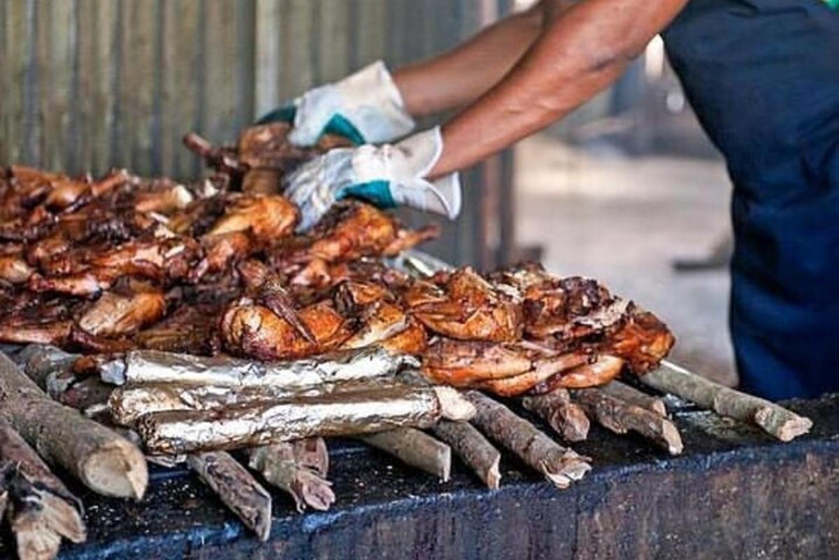 ein Mann steht neben einem Grill mit einem Haufen Essen