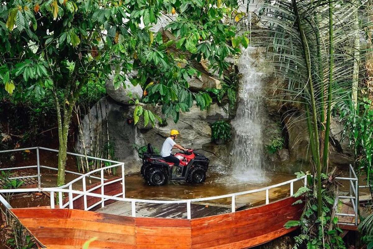 seorang lelaki menunggang basikal quad di hadapan air terjun