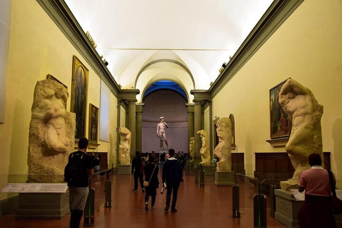 un gruppo di persone che camminano in un museo con statue