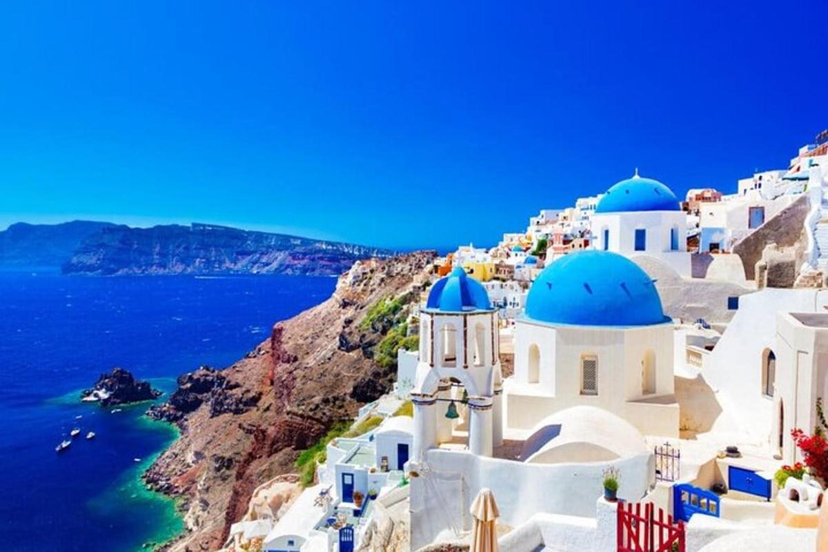 Μια ομάδα λευκών κτιρίων με μπλε θόλους σε έναν απότομο βράχο