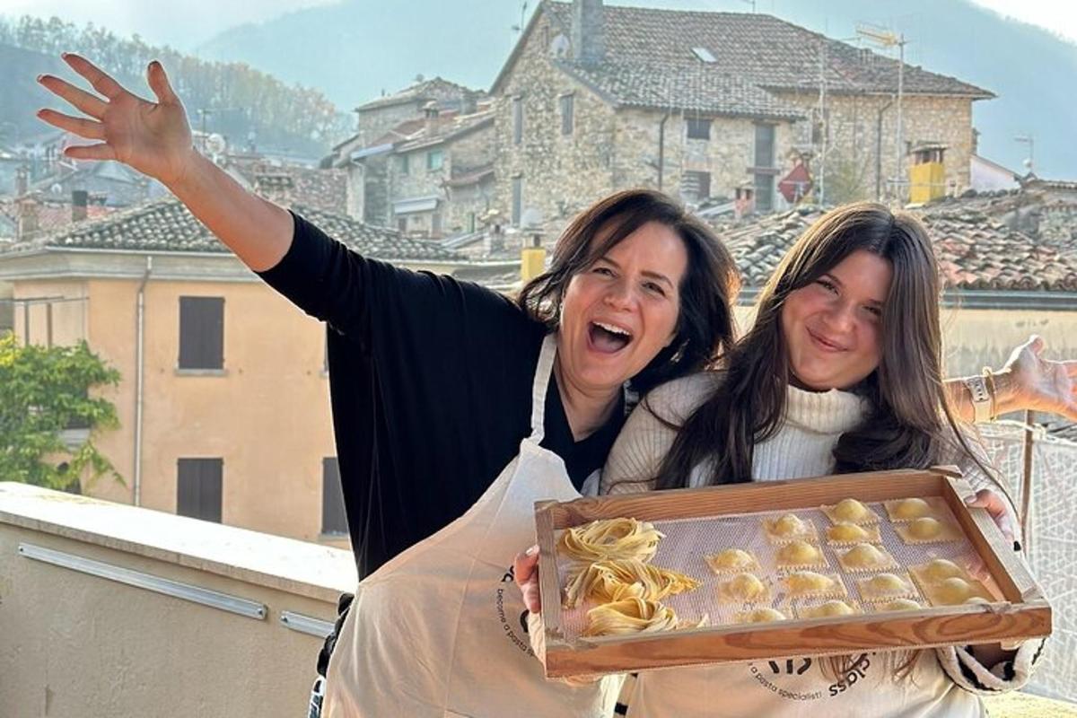 due donne in piedi su un balcone con in mano una scatola di pasticcini