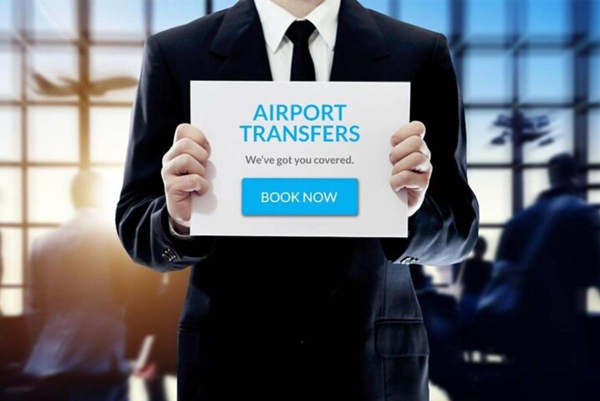 muž v obleku držící ceduli s nápisem „letištní transfery“