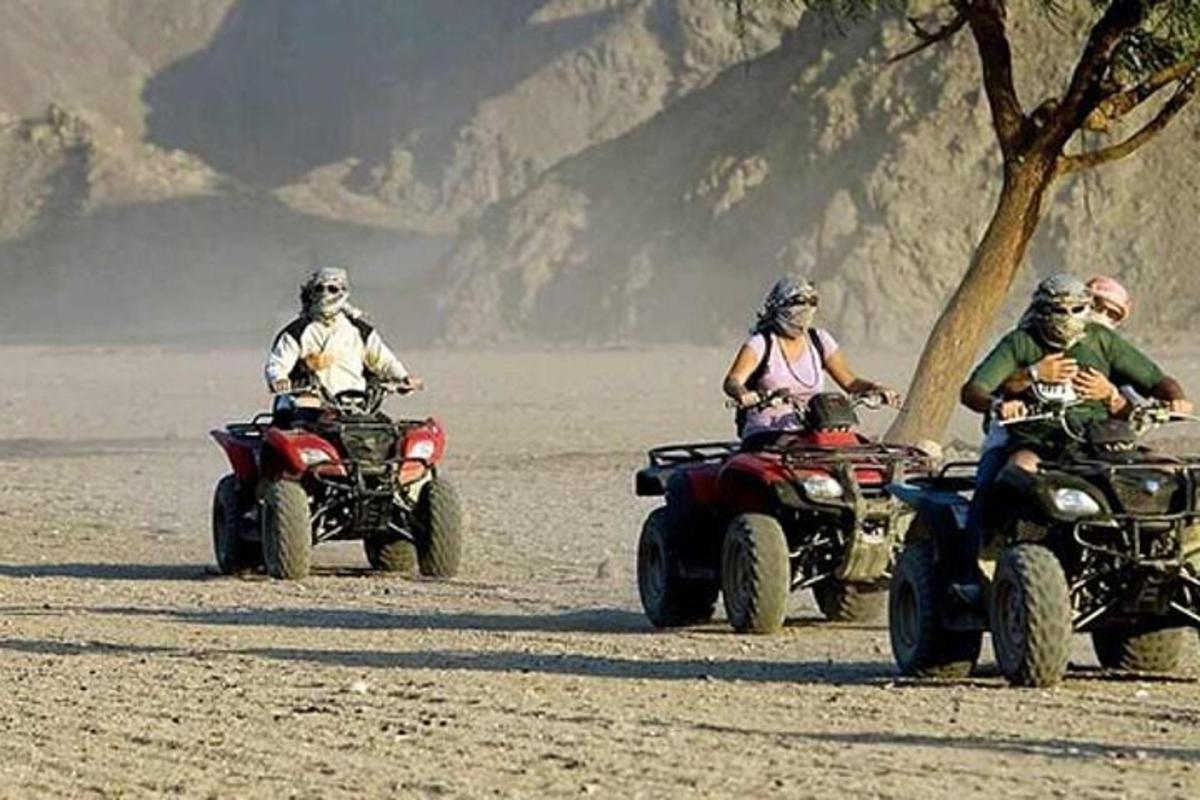 sekumpulan orang menunggang atv di padang pasir